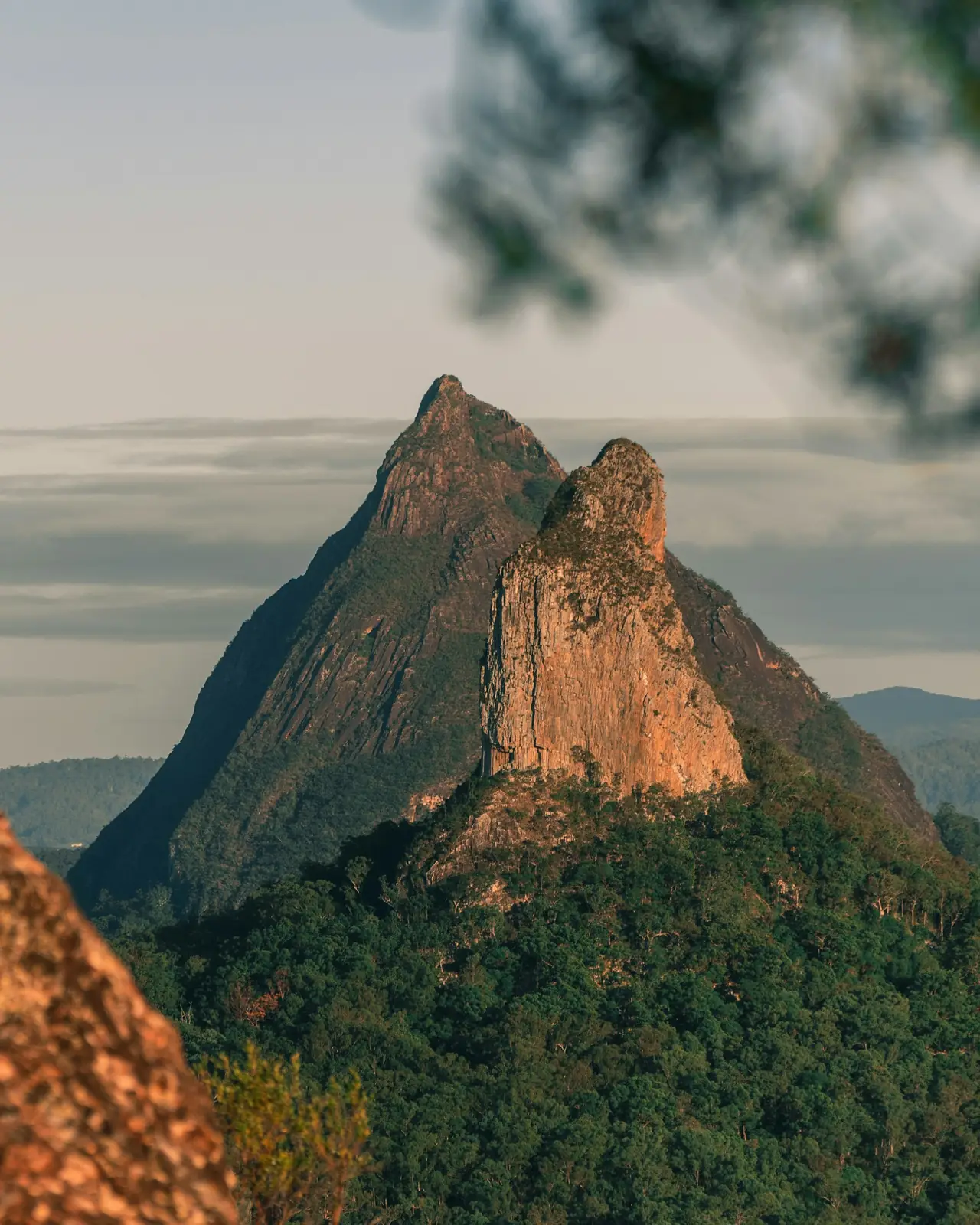 A craggy volcanic peak rising over forest