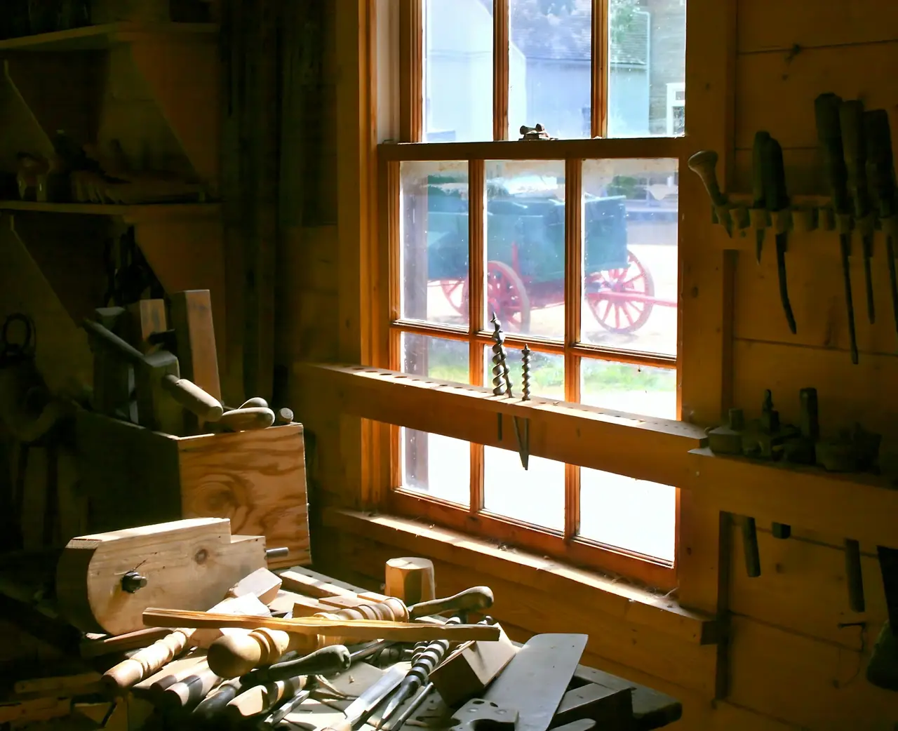 A workbench under a sunny window, tools hanging on the timber wall