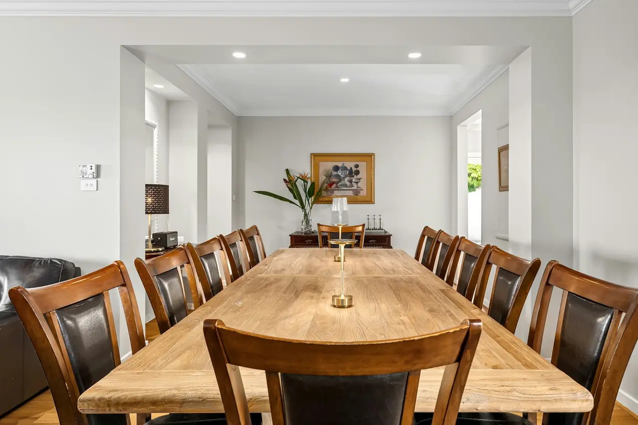 A long timber dining table with leather chairs in a bright room
