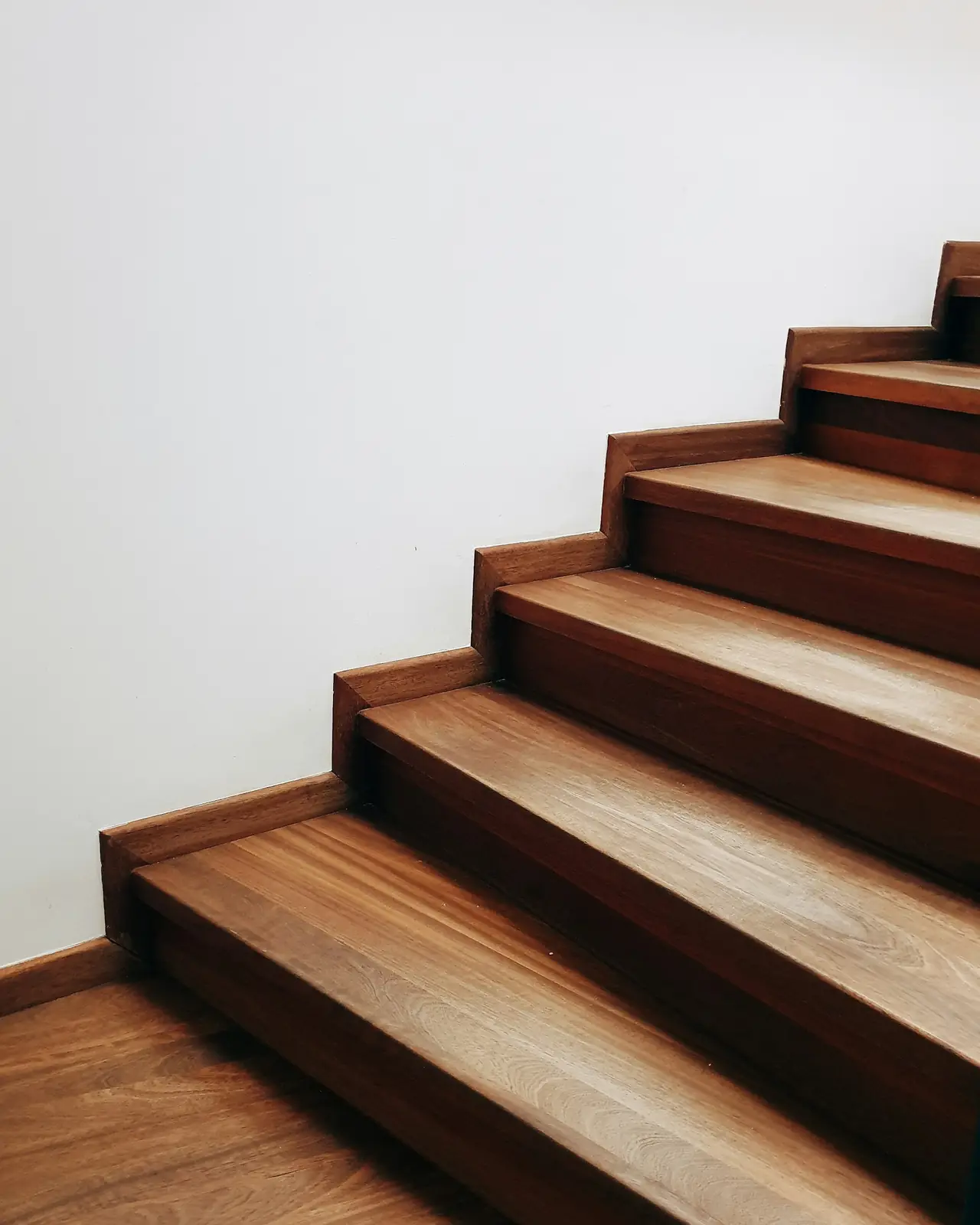 Hardwood stair treads climbing a white wall