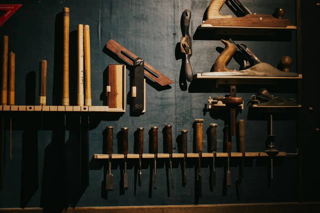 Hand planes, chisels and marking tools hanging on a dark workshop wall