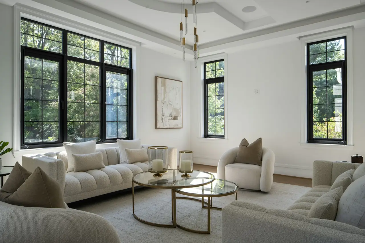 A bright living room with pale sofas and tall black-framed windows