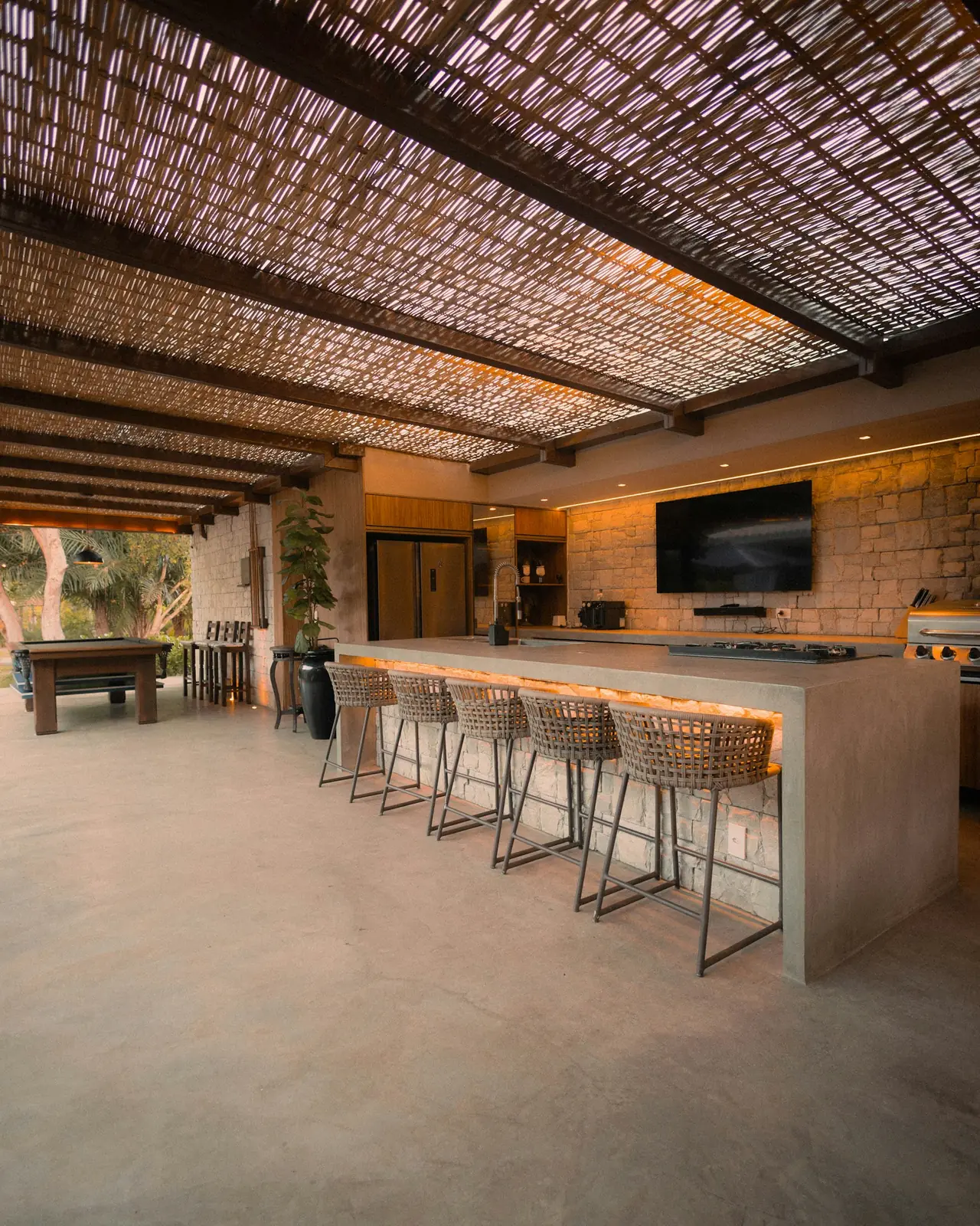A covered outdoor kitchen and bar under a timber batten roof