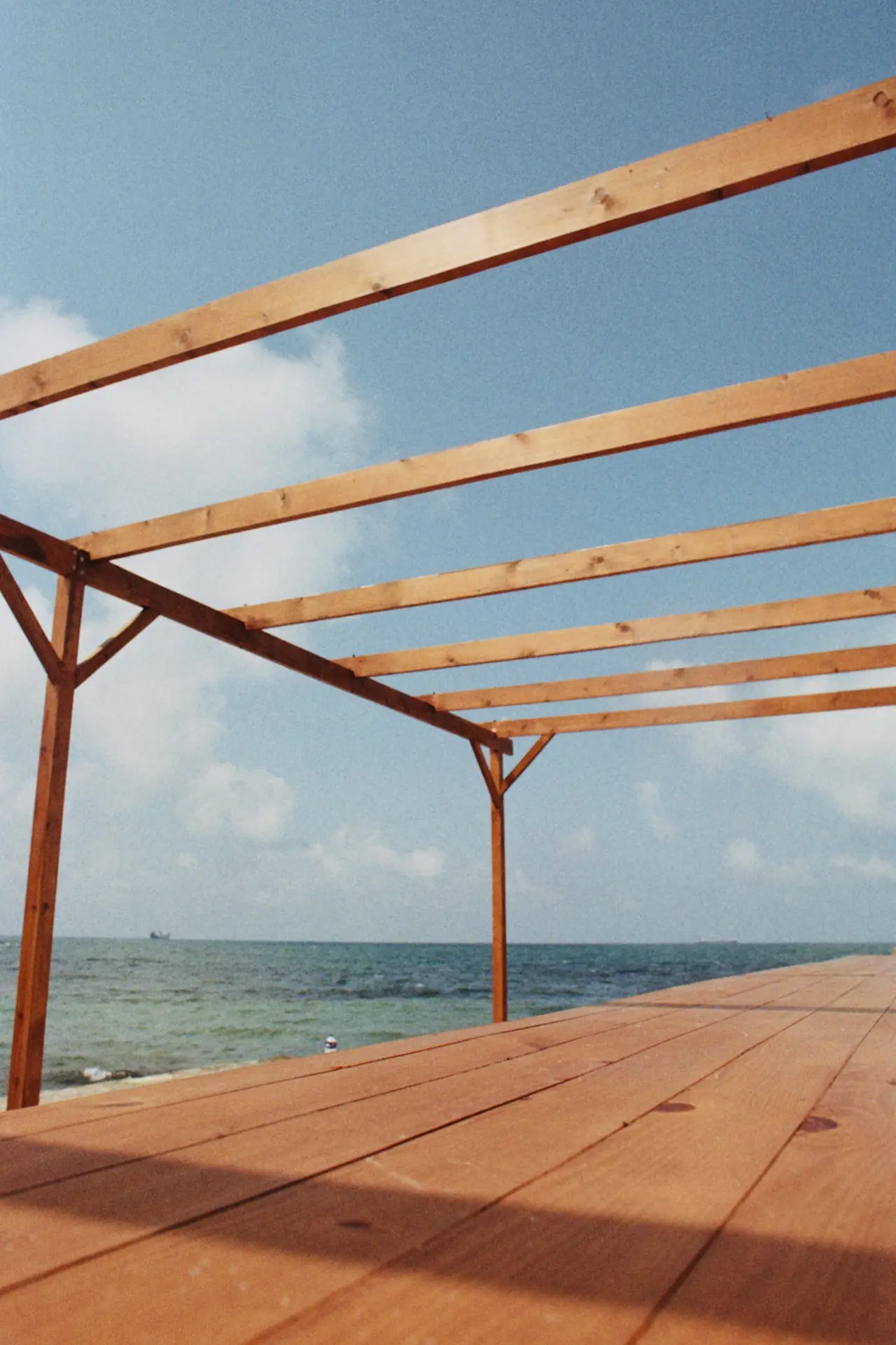 A timber deck and pergola frame looking out to the water