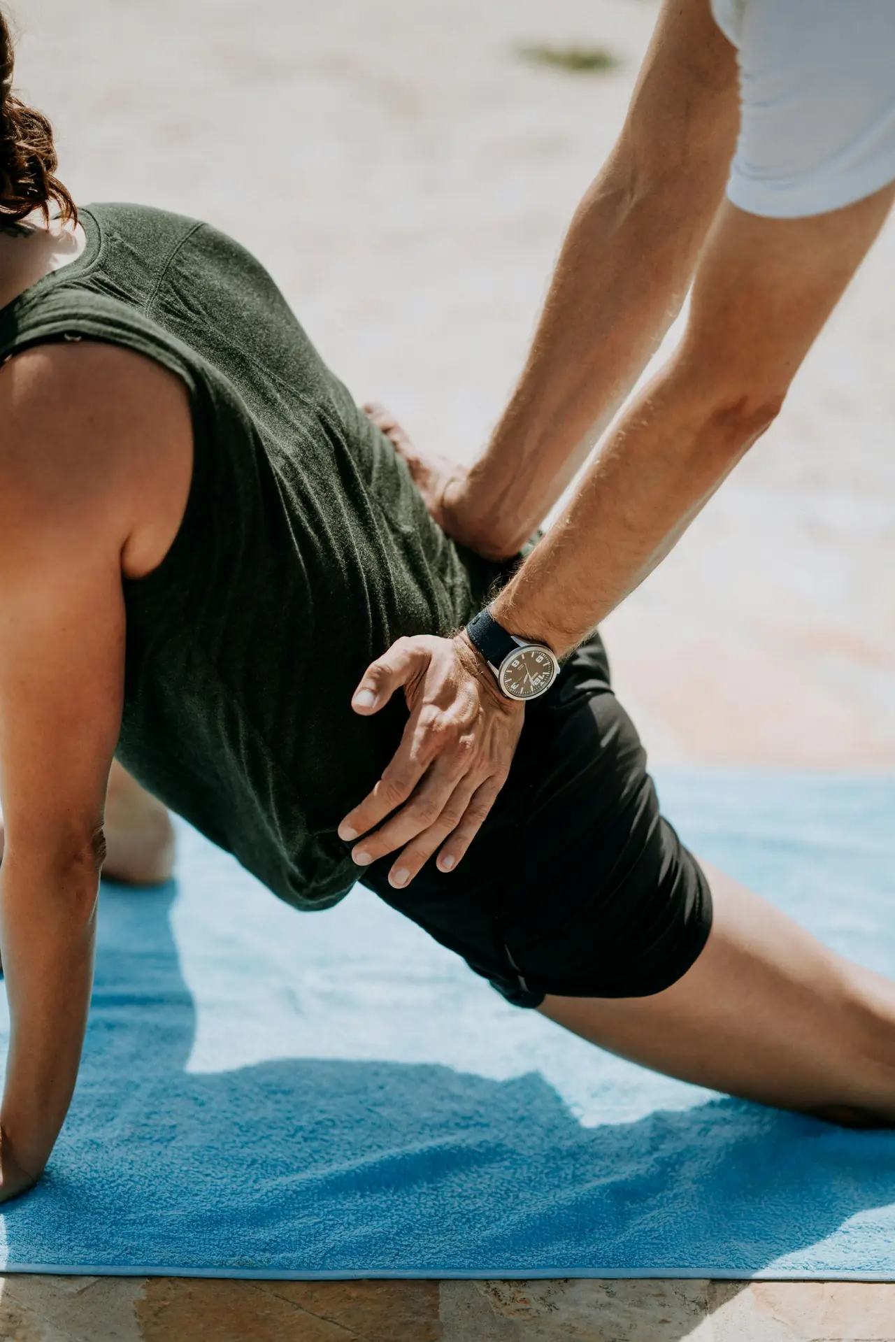 A physiotherapist guiding a client through a lunge stretch on a mat