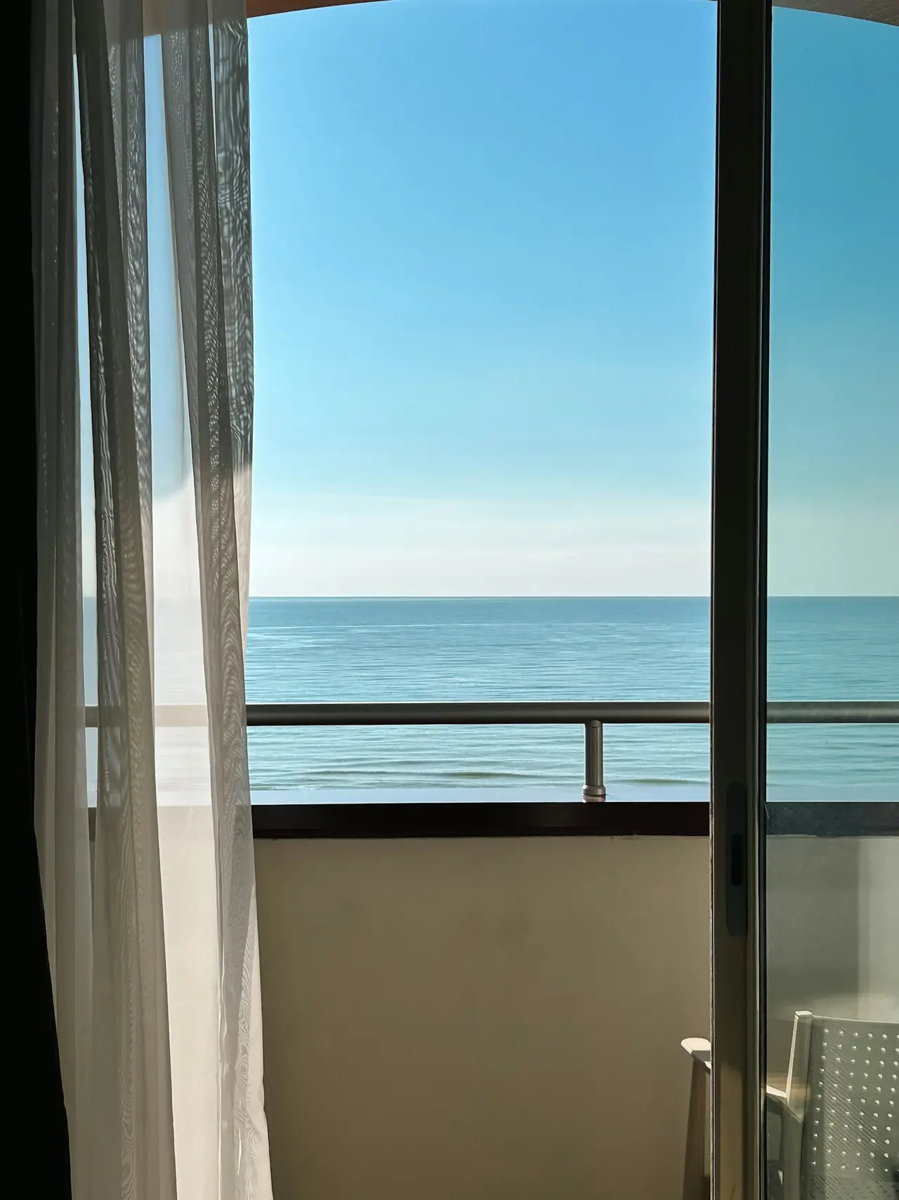An open balcony door looking straight out to the ocean