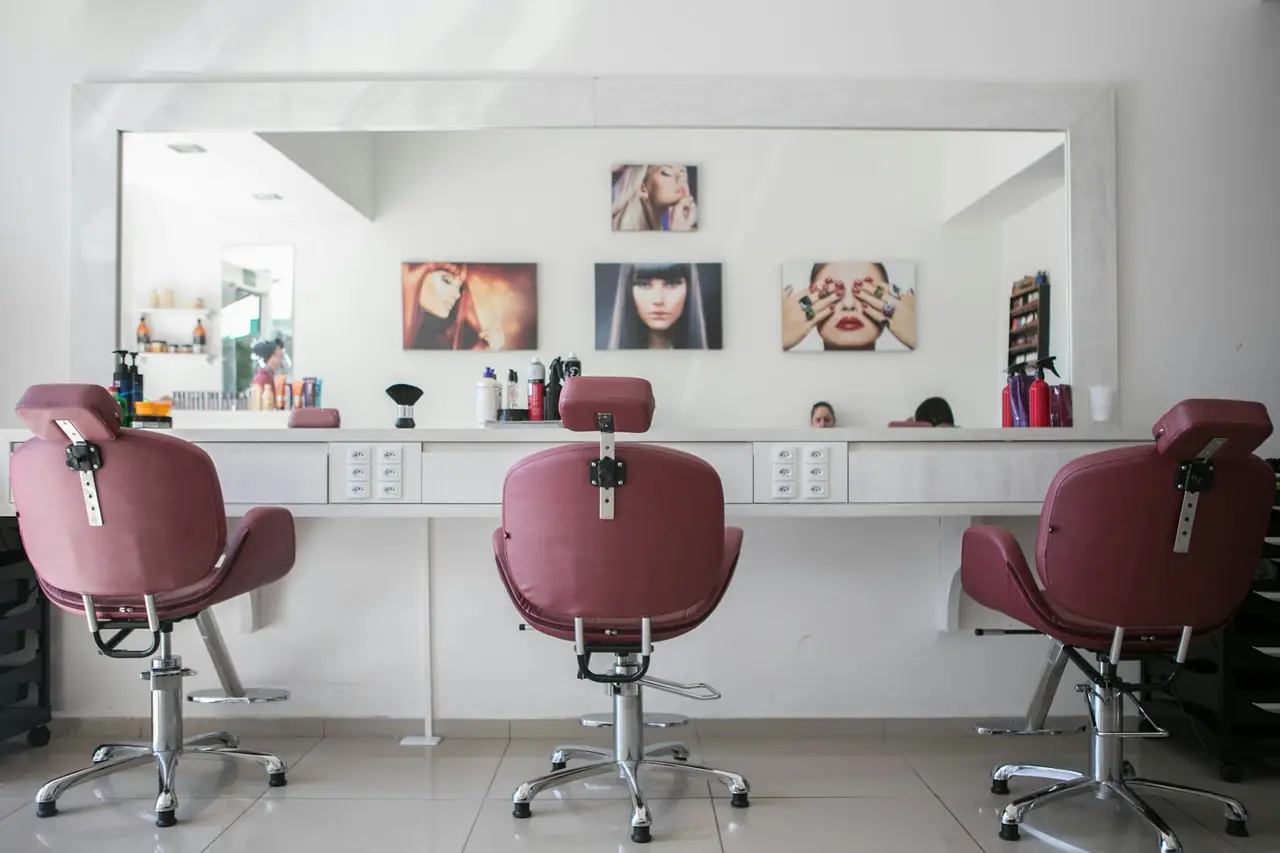 Three plum salon chairs in front of a long mirror